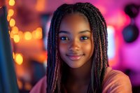 Young African American woman with box braids smiling at camera against blurred festive background with bokeh lights and pink neon glow, expressing joy and confidence.