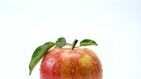 Fresh red apple with green leaves and water droplets isolated on white background for healthy eating and nutrition concepts.
