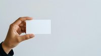Male hand with medium skin tone holding blank white business card against neutral background, suitable for branding and corporate design projects.
