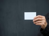 Mature man with light skin tone holding blank white business card against dark textured background. Suitable for corporate branding, networking, contact information, and professional identity design.