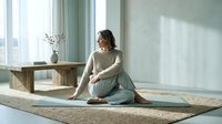 Young woman practicing mindful meditation in serene home interior with natural light streaming through windows creating peaceful atmosphere for wellness.