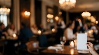 Woman holding blank white menu card at upscale restaurant dinner event with blurred elegant dining room background and guests celebrating.