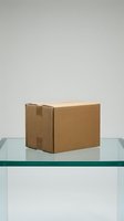 Brown cardboard shipping box on glass table against neutral background for delivery and logistics concepts.