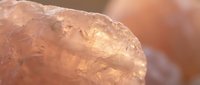 Close-up of rough rose quartz crystal with natural texture and warm pink coloration for healing, meditation and spiritual wellness practices.