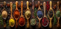 Colorful spices and herbs in wooden spoons arranged in row on dark background, overhead panoramic view. Fresh seasoning collection for cooking.