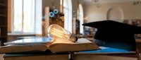 Graduation cap and glowing light bulb on open books symbolizing education achievement and bright ideas for academic success and learning.
