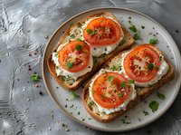 Fresh tomato and mozzarella open sandwiches on toasted bread garnished with herbs and black pepper, served on ceramic plate against gray background.