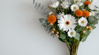 Fresh spring bouquet with white gerbera daisies, orange craspedia, eucalyptus leaves and peach hypericum berries on light gray background. Floral arrangement for wedding decor.