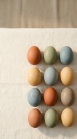 Naturally dyed Easter eggs in earth tones arranged on linen fabric with wooden background for spring holiday crafts and seasonal decorating projects.
