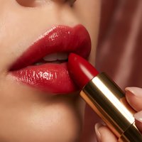 Woman applying red lipstick with golden tube close-up beauty makeup cosmetics routine for fashion and glamour advertising campaigns.