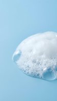 White soap bubble with foam texture floating against light blue background, suitable for skincare, cosmetics, and wellness product marketing.