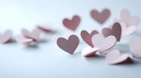 Pink paper hearts scattered on light surface with soft shadows, romantic minimal composition for valentines day cards and wedding designs.