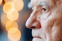 Close up profile portrait of senior man with wrinkled skin against blurred warm bokeh lights background showing contemplative peaceful expression.