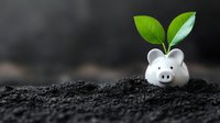 White piggy bank with green plant growing from top placed in dark soil, representing financial growth, savings, and sustainable investment concepts.