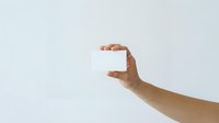 Hand holding blank white card or business card mockup against neutral background for branding and marketing presentations.