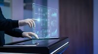 Business professional interacting with futuristic holographic data interface displaying charts and analytics in modern office environment.