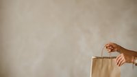 Person with medium skin tone holding kraft paper shopping bag, suitable for retail, commerce, and consumer lifestyle content.