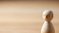 Minimalist wooden figure on natural wood surface with warm lighting and copy space for design projects and presentations.