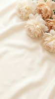 Soft peach and cream peonies arranged on flowing silk fabric creating elegant romantic atmosphere for wedding invitations and feminine design projects.