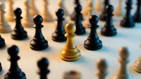 Golden chess pawn standing out among black pieces on board, symbolizing leadership, strategy, uniqueness and competitive advantage in business game.