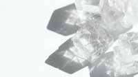 Clear ice cubes melting on white surface with dramatic shadows creating abstract patterns for beverage and cooling concepts.