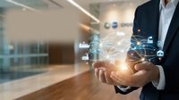 Professional businessman holding glowing digital network connections with technology icons in modern office environment for business innovation concepts.
