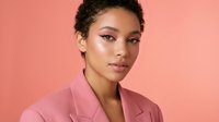 Young African American businesswoman in pink blazer with confident expression against coral background for professional headshot and corporate branding.
