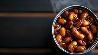 Smoked kidney beans in metal tin with steam rising, glazed in sweet sauce, photographed from above on dark wooden background with copy space.