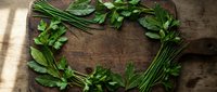 Fresh green herbs arranged in heart shape on rustic wooden background for cooking, healthy eating and culinary design projects.
