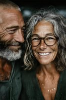 Happy senior couple laughing together showing genuine joy and connection in intimate portrait. Mature man with gray beard and woman with glasses embracing warmly.