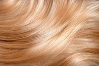 Close-up of flowing blonde hair texture showing smooth, silky strands with natural highlights and waves creating dynamic movement pattern. For beauty and hair care designs.