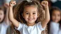 Happy young girl with curly hair raising arms in victory gesture, wearing white t-shirt against blurred background, expressing joy and achievement.