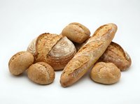 Assorted fresh baked bread loaves and rolls isolated on white background, including baguette and round artisan loaves for bakery, food, and culinary design use.