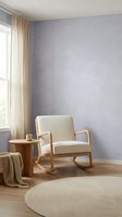 Serene reading nook with cream rocking chair, wooden side table, and round beige rug in minimalist bedroom with lavender walls and natural light from window.