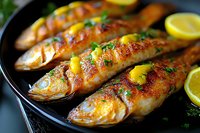 Grilled whole fish with crispy golden skin, garnished with fresh lemon slices and herbs on black plate, close-up view of seafood dinner preparation.