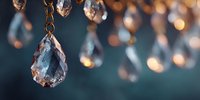 Elegant crystal chandelier with sparkling glass drops creating warm bokeh lights against dark blue background for luxury interior design and lighting decor.