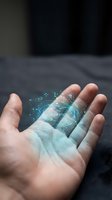 Hand holding glowing digital hologram with flowing data particles and network connections, representing technology, innovation, and future digital transformation concepts.