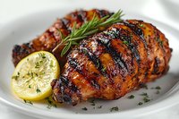 Grilled chicken breast with charred grill marks, glazed in honey marinade, served with fresh rosemary sprig and charred lemon half on white plate. Juicy meat texture.