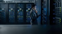 IT technician working in modern data center server room with network equipment and blue lighting for technology infrastructure maintenance.