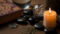 Mystical fortune telling setup with tarot cards, crystal ball, burning candle and pentagram symbol creating atmospheric divination scene for spiritual practices.