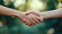 Two hands shaking in agreement against soft green bokeh background symbolizing partnership, cooperation, teamwork and successful business deal.