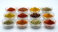 Colorful spices and herbs collection in glass bowls arranged on white background for cooking, seasoning and culinary preparation in kitchen.