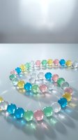 Colorful translucent glass beads arranged in spiral pattern on white surface with soft studio lighting, suitable for jewelry design and craft projects.