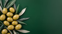 Fresh green olives with leaves arranged on dark green background, natural organic food styling for Mediterranean cuisine and healthy eating concept.