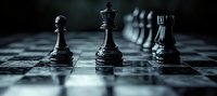 Black chess pieces on board in dramatic lighting, close-up view with selective focus showing queen, bishop and rook figures against blurred background.