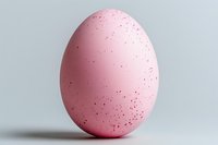Pink speckled egg isolated on light gray background, perfect for Easter designs, spring themes, and minimalist compositions.