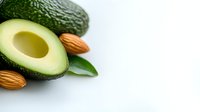 Fresh cut avocado half with raw almonds and green leaves on white background, healthy fats and nutrients concept for food photography and design.