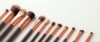 Professional makeup brush set with rose gold ferrules and black handles arranged in row on white background for beauty and cosmetics applications.