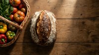 Fresh artisan sourdough bread loaf with colorful heirloom tomatoes in wicker basket on rustic wooden table for farm-to-table cooking and baking concepts.