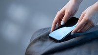 Woman hands with light blue manicure placing smartphone on gray fabric surface, soft bokeh background, technology and lifestyle concept.